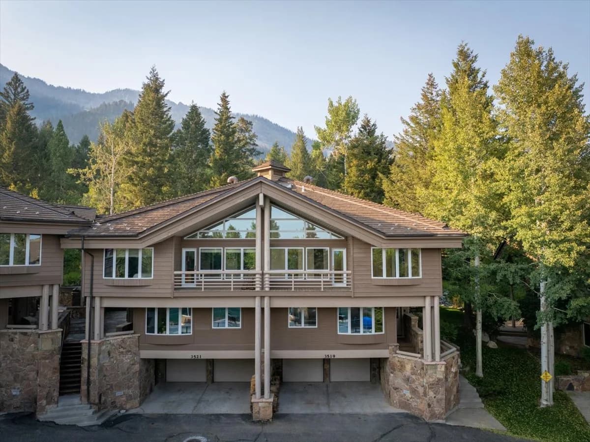 Mountain condo building exterior with forested backdrop