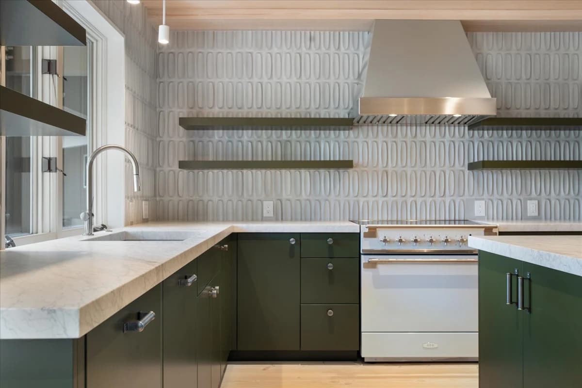 Close-up of green kitchen cabinetry with textured tile backsplash