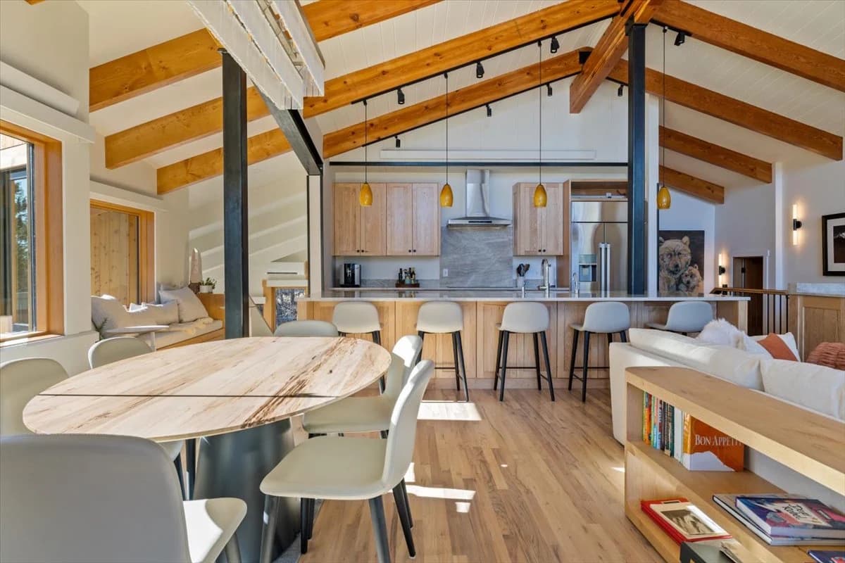 Open-concept kitchen, dining, and living space with vaulted wood beam ceiling