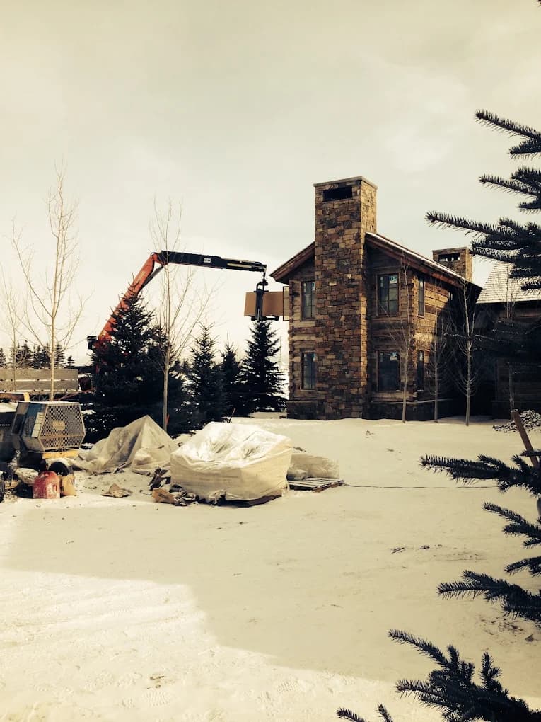 Construction site with crane lifting stone chimney materials