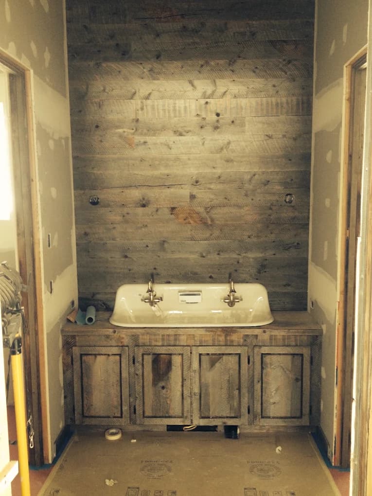 Bathroom mid-construction with trough sink and reclaimed wood wall