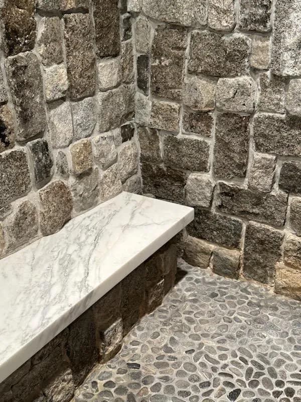 Stone-walled spa bench with marble seat and pebble floor